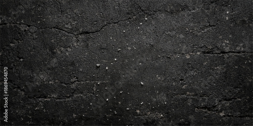 Rough black asphalt texture reveals a dark weathered stone pattern on an old bitumen road surface with a grainy gray tarmac pavement material