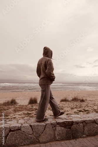 Woman walking alone on the coast. Concept of escape, journey, or mental health struggles.