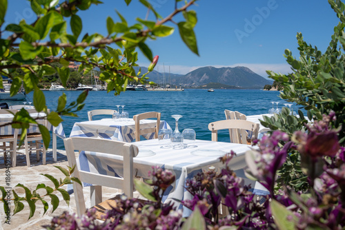 Foto Served tables in a Greek tavern in Vathy Harbor, Meganisi island, Ionian Sea, Greece during the summer tourist season
