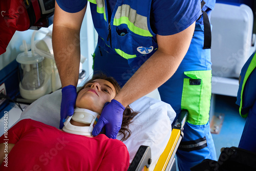 Ambulance medic assisting female patient with neck brace