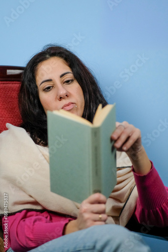  Woman reads a book while flipping through the pages. The woman is thirty-nine years old, has long black hair and is of Caucasian origin