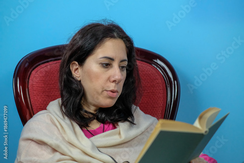  Woman reads a book while flipping through the pages. The woman is thirty-nine years old, has long black hair and is of Caucasian origin