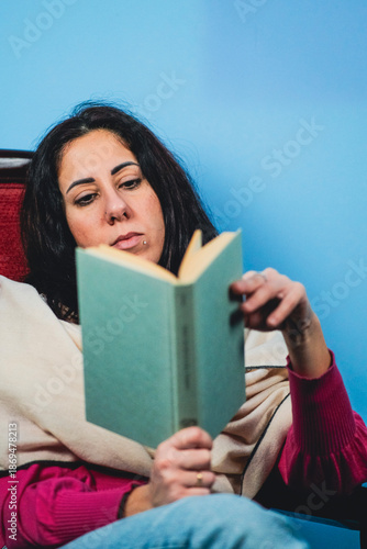  Woman reads a book while flipping through the pages. The woman is thirty-nine years old, has long black hair and is of Caucasian origin