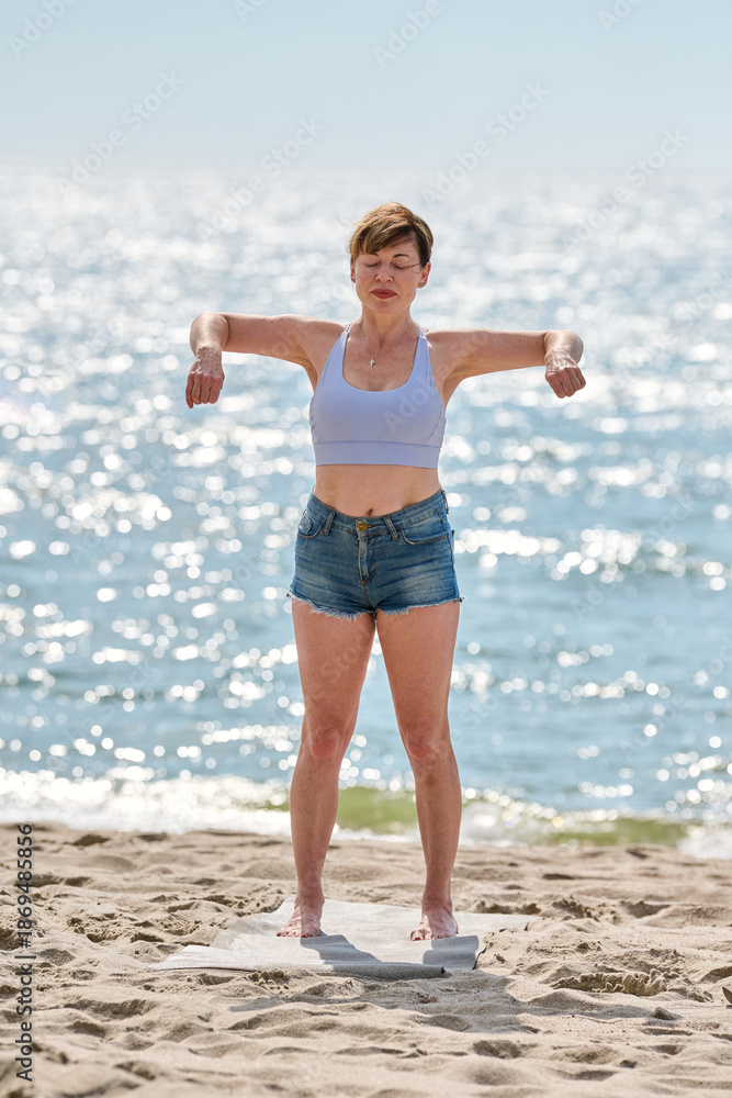 Fototapeta premium Young woman practicing yoga exercise with mindfulness on Baltic Sea beach