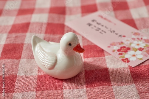 White Ceramic Duck Figurine with Pink Envelope on Red Gingham Cloth