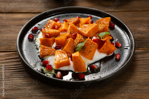 Sliced roasted butternut pumpkin with greek yogurt on plate wood surface