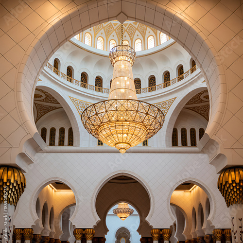 Interior of a large mosque with white arches and a large chandelier