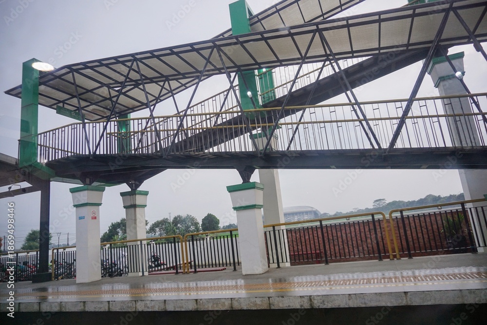 Obraz premium Pedestrian overpass with steel structure and protective roof in an urban area.