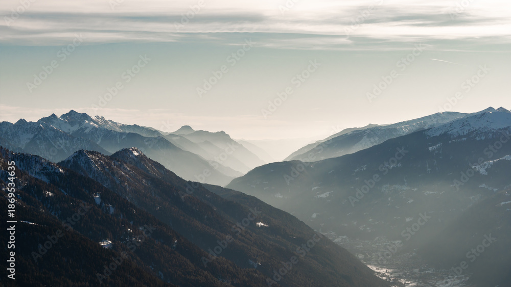 Naklejka premium View to Pinzolo village in the valley of Italian Alps mountains during ski resort winter season, sport and tourism