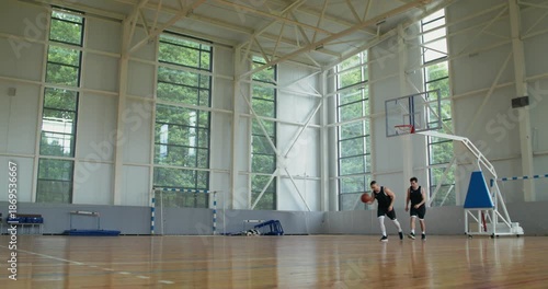 Two players compete in basketball on a basketball court.. two basketball players play basketball with one hoop.