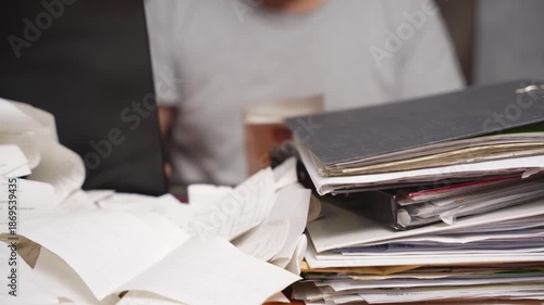 Office Stress and Administrative Burden. Overworked person handling stacks of papers and folders at a desk. Symbol of office stress, bureaucracy, deadline pressure, and administrative workload.