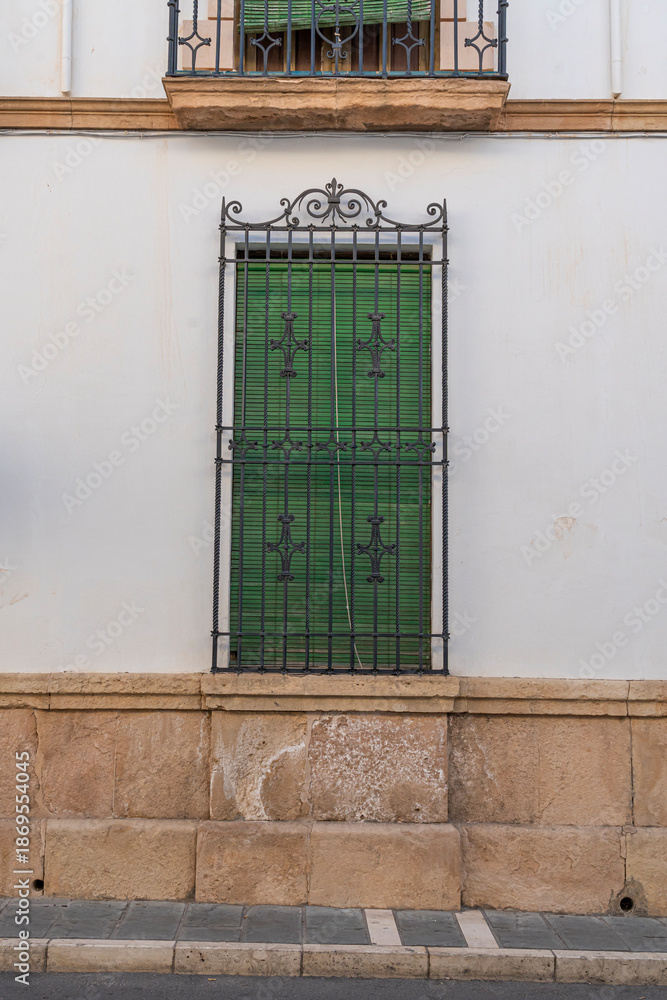 Obraz premium Green window with decorative ironwork on white wall.. Ronda, Málaga, Spain