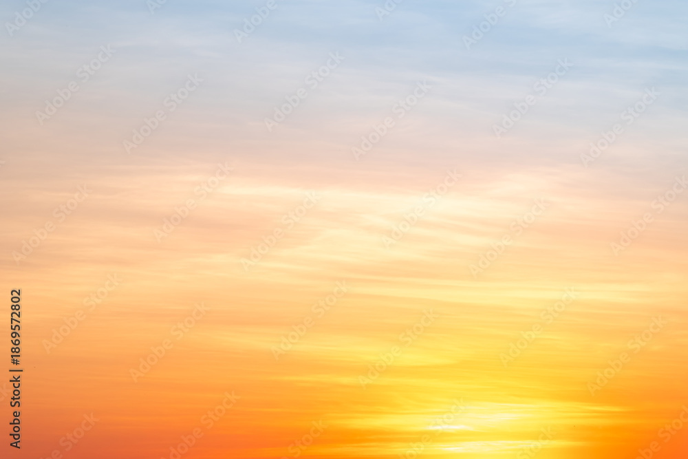 Fototapeta premium Sunset or sunrise sky with a vibrant gradient of orange, gold, and soft blue. Clear atmosphere with wispy clouds. Peaceful, natural light background. hope, freedom, new day and inspirational Concepts
