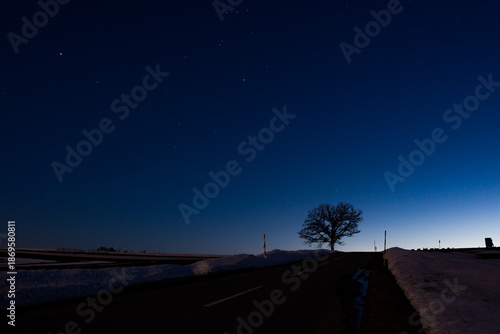 春の雪解けの丘と夕暮れの星空

