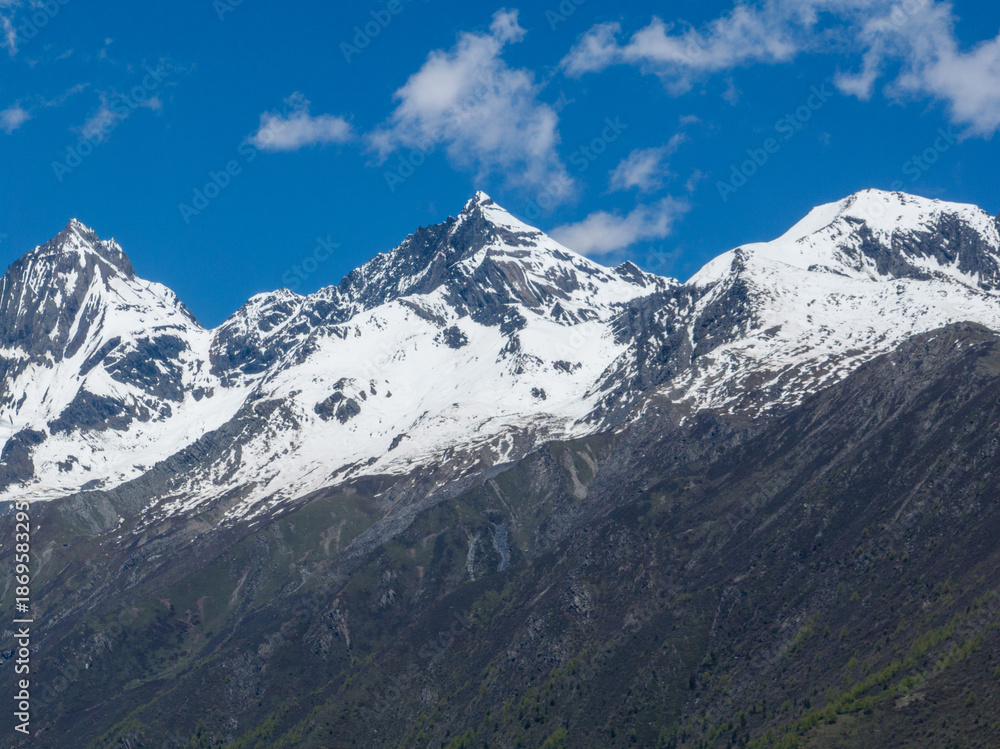 Fototapeta premium Aerial view of beautiful high altitude snow capped mountain and forest landscape