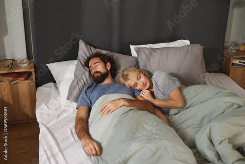 Fotografia A man and woman are peacefully asleep in a shared bed, wrapped in soft blankets, demonstrating warmth and comfort in a cozy bedroom setting