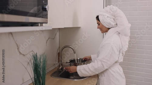 Woman bathrobe, Hydration health, Water benefits. In kitchen, woman wearing bathrobe partakes in healthy act drinking uncontaminated water.