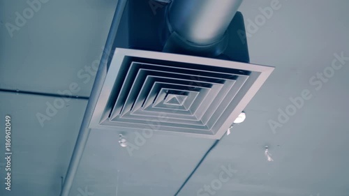 Gray ventilation pipe with a grill near the ceiling in a warehouse building. Shot in motion