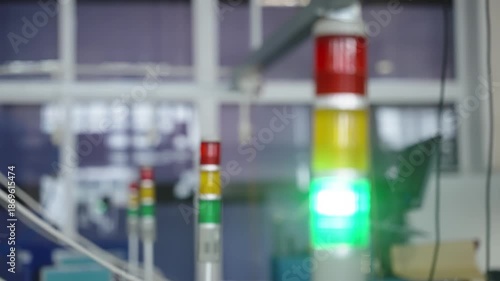 Close-up view of an industrial stack light tower with red, yellow, and green status indicators in a modern factory environment, signaling safety status and production monitoring