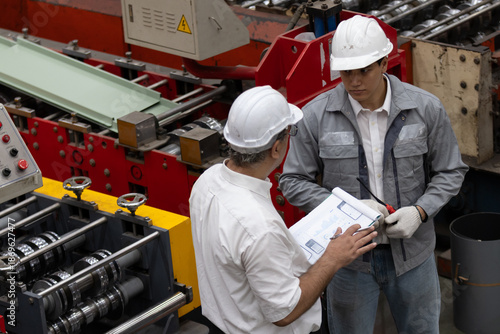 Team of Industrial Engineer in Hard Hats Work at the Heavy Industry Metal Sheet Manufacturing Factory. Factory worker indoors in metal sheet factory. Man working in an industrial factory. 