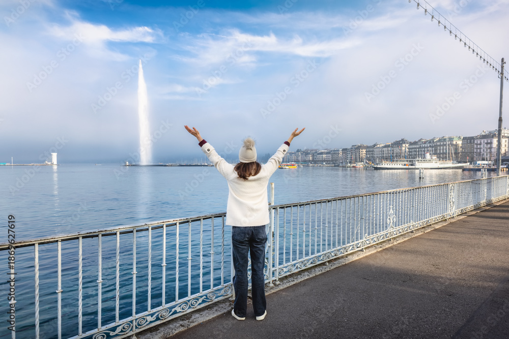 Naklejka premium Rear view of a happy tourist woman looking at the famous Lake Geneva during a moody winter day with fog and sunshine, Switzerland