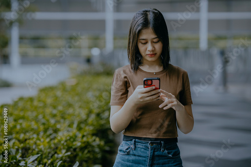 Beautiful young asian woman using mobile phone apps in city.