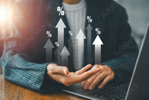 Businessman in suit analyzing financial growth with percentage arrows, using a laptop in a modern office environment.