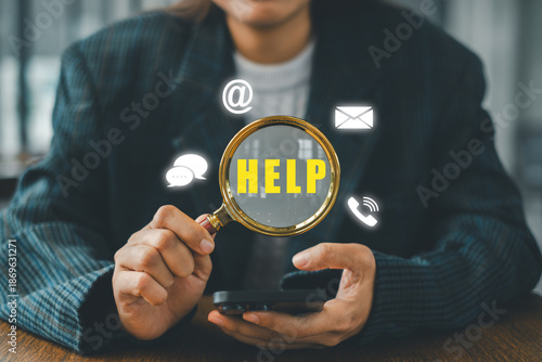 Businesswoman holding a magnifying glass over help icons, symbolizing communication and support in a digital environment.
