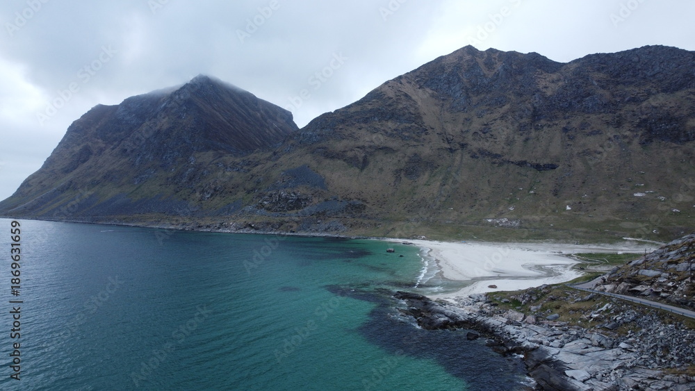 Obraz premium Aerial view of a turquoise mountain lake surrounded by rugged terrain. Clear water contrasting with rocky landscape, photographed from a drone.