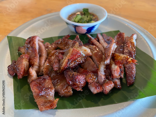Thailand street food, grilled pork neck with Thai dipping sauce, close-up shot blurred background, no people.