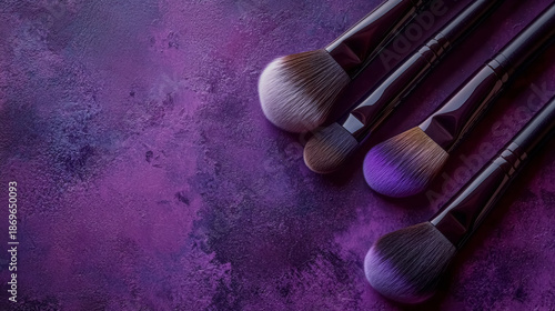 Four natural soft makeup brushes with varying bristle shapes and sizes on dark purple background with copy space, professional tool for applying cosmetics