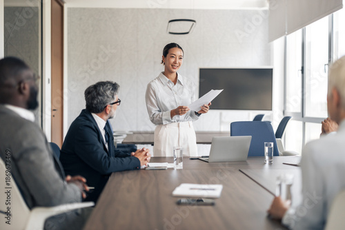 Asian businesswoman presenting to diverse team in office meeting