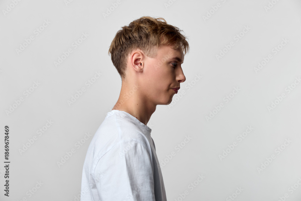 Obraz premium Profile view of a young man in a white shirt against a plain backdrop, conveying calm, focus and minimalism, suitable for lifestyle, fashion, and creative concepts in stock photography