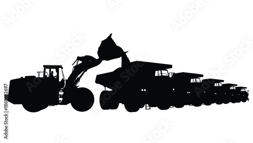 Silhouette of a front loader dumping into a large dump truck