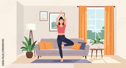 Young woman practicing yoga tree pose on a mat in a bright and cozy modern living room with a sofa plants and large window.