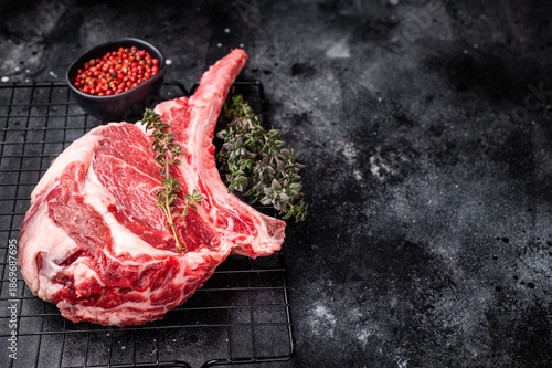 Uncooked tomahawk steak, raw black angus beef rib eye with bone. black background. top view