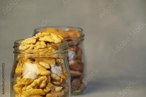 Nuts in a clear glass container on a gray background with copy space