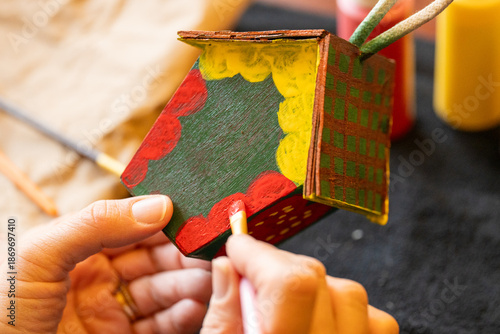 Obraz na płótnie Shallow DOF image of woman painting a small birdhouse arts and crafts concept