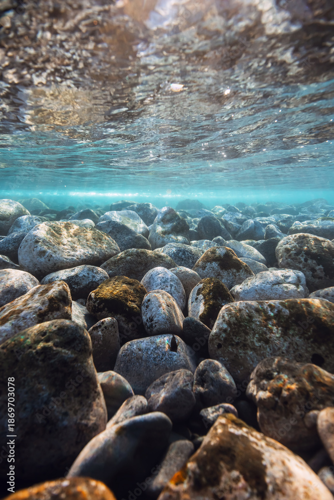 Fototapeta premium Underwater landscape with stones sea bottom and sun rays in water.
