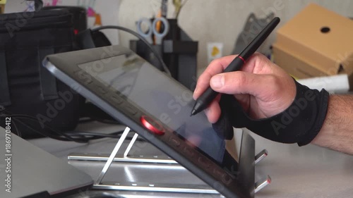 Drawing on a graphics tablet. Male hand. Digital artist. Room. Daylight. Close-up. Faceless. Creativity