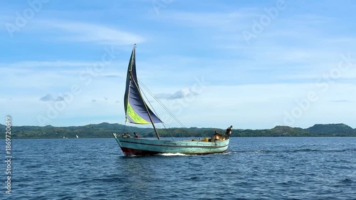 Sailing on a small wooden boat in clear blue water under a bright sky with distant hills present
