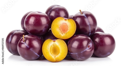 A pile of purple plums with one cut open to reveal a yellow interior.