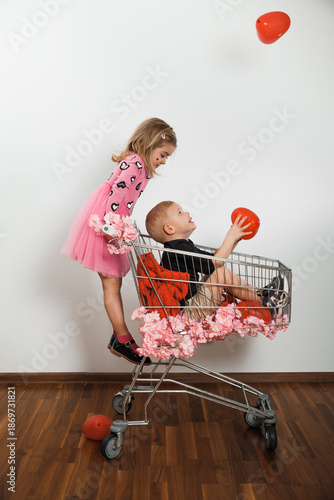 Obraz na płótnie Children play with red balloons in shopping cart at indoor location during dayti