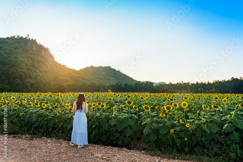 Wallpaper Mural Back view of beautiful woman on farm in field of blooming sunflowers on summer day with mountain in background. Woman in Sunflower Field. Happy female in vast field of sunflowers with mountain view. Torontodigital.ca