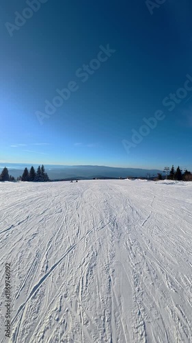 Beautiful POV ski landscape on the mountains. Skier skis down a snowy mountain trail in sunny weather.