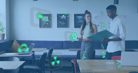 Reviewing two colleagues holding folder and tablet in cafe with laptops and holographic icons