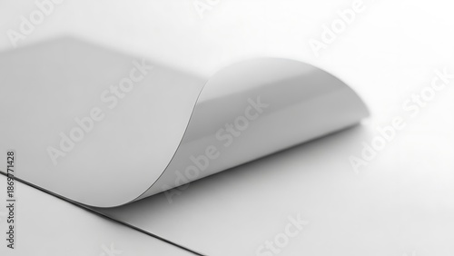 A sheet of paper with one corner curled up. The light reveals the texture and shape of the paper, inviting a closer look. The composition is simple, yet elegant