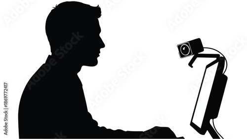 Man sitting at desk with computer and webcam in profile view, working or video conferencing in modern office setting with technology