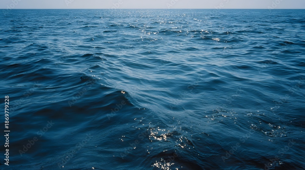Fototapeta premium Vast expanse of deep blue ocean water with gentle waves under a clear sky