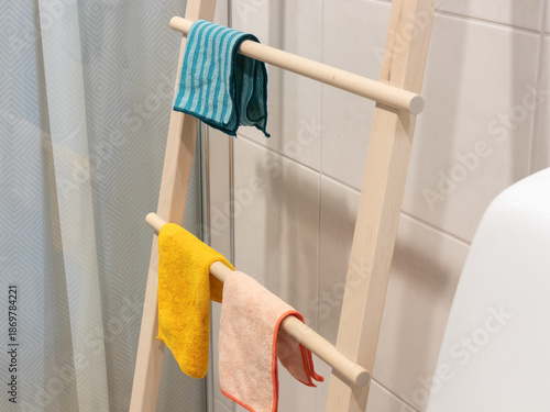 Fotografia Drying cloths hang neatly on a leaning wooden towel stand, offering a stylish an
